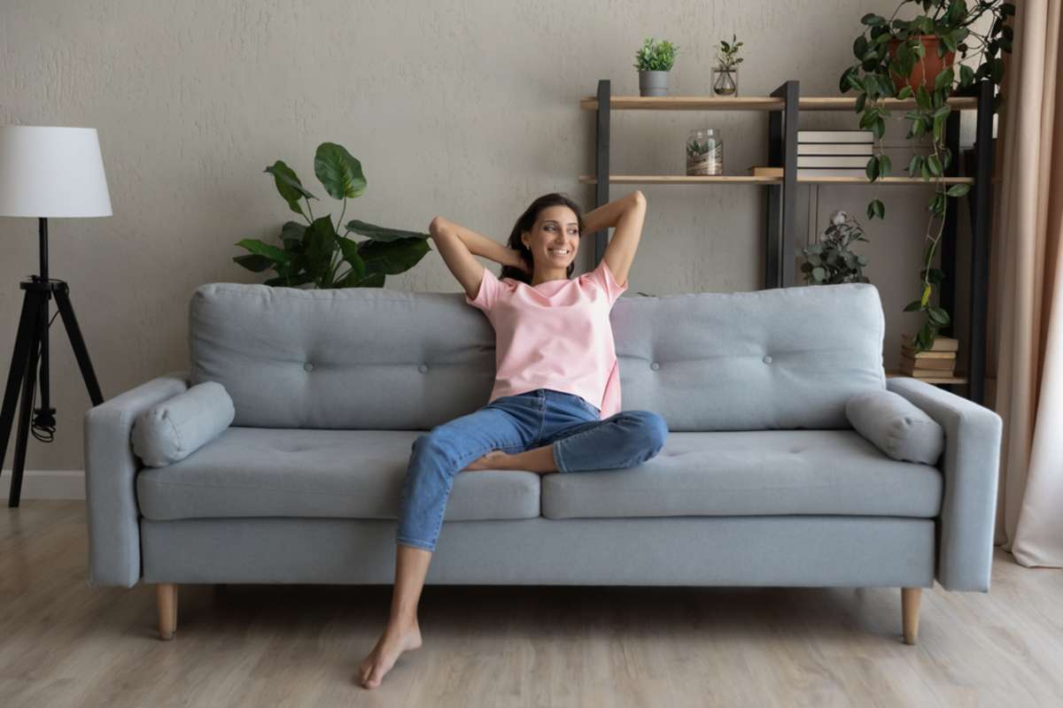 Happy millennial indian Arabic woman sit rest on comfortable couch