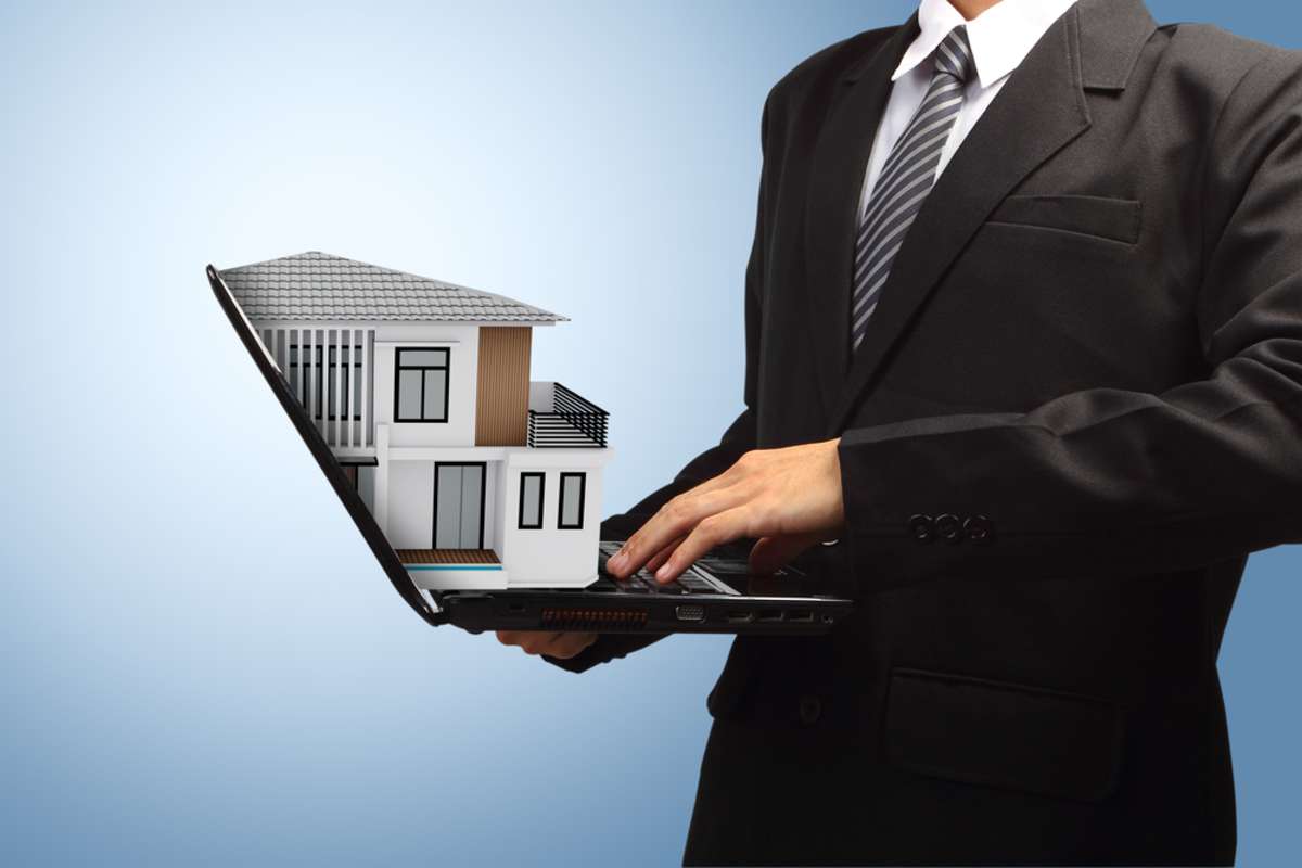 Business man using laptop with house model house concept in the hand