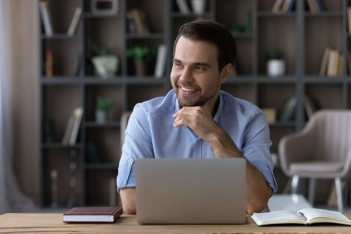 Distracted from computer work handsome young businessman looking in distance