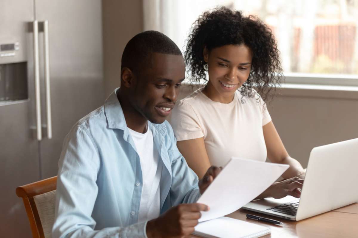 Happy african american family couple sitting at home with laptop