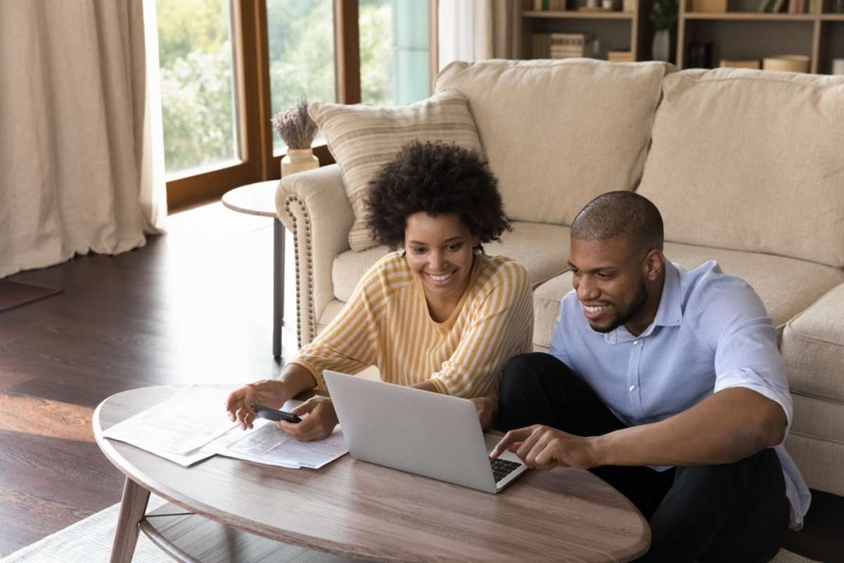 Happy millennial african american family couple analyzing financial paper documents