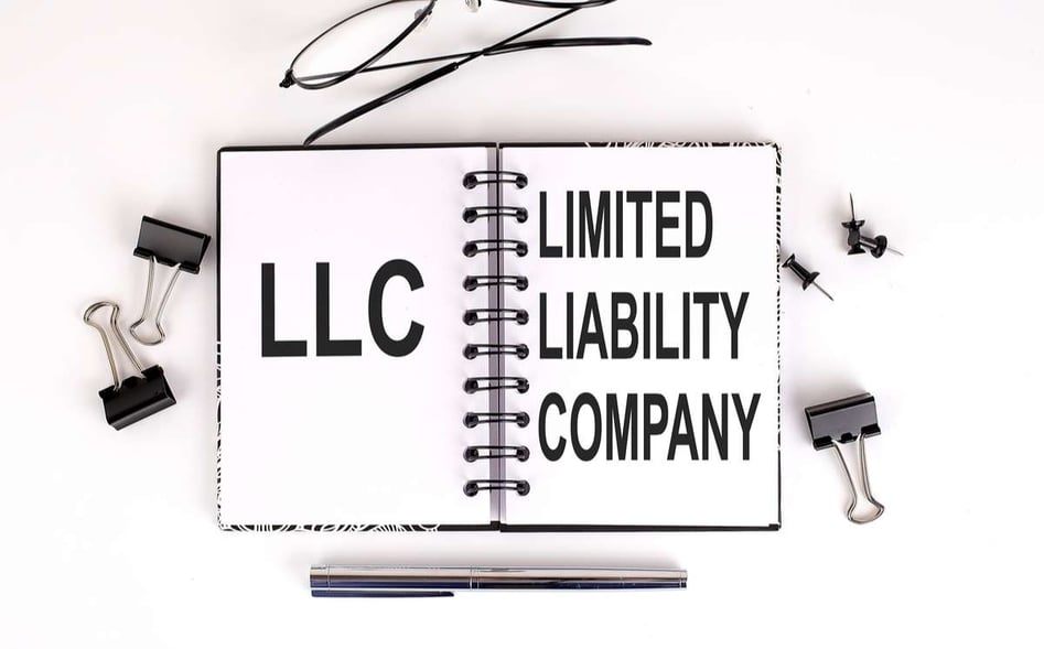Notebook with LLC Limited Liability Company on the table with office tools