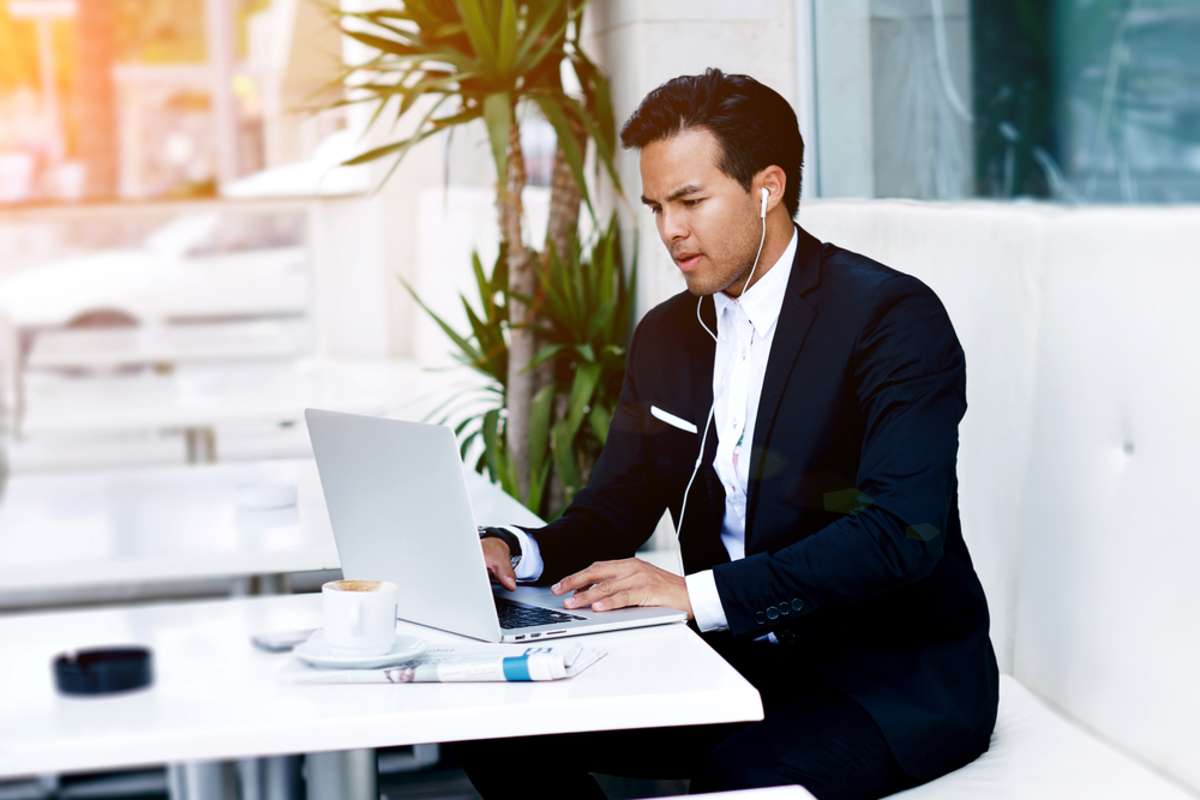 Young entrepreneur with headphones having on-line meeting using net-book