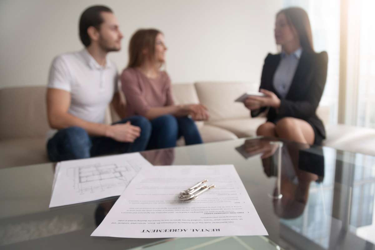 Young renters couple sitting on couch discussing renting apartment