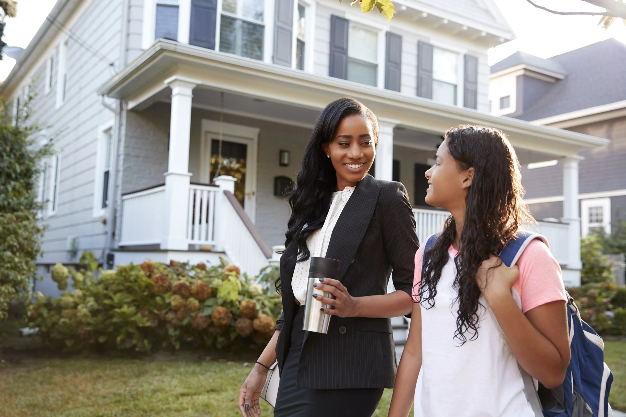 Business woman walking with daughter through neighborhood