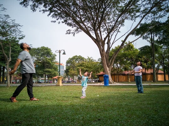 A father and his two daughters playing in a neighborhood park