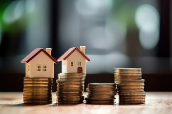 Small houses sitting on stacks of money