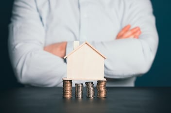 A model home propped up on level stacks of coins