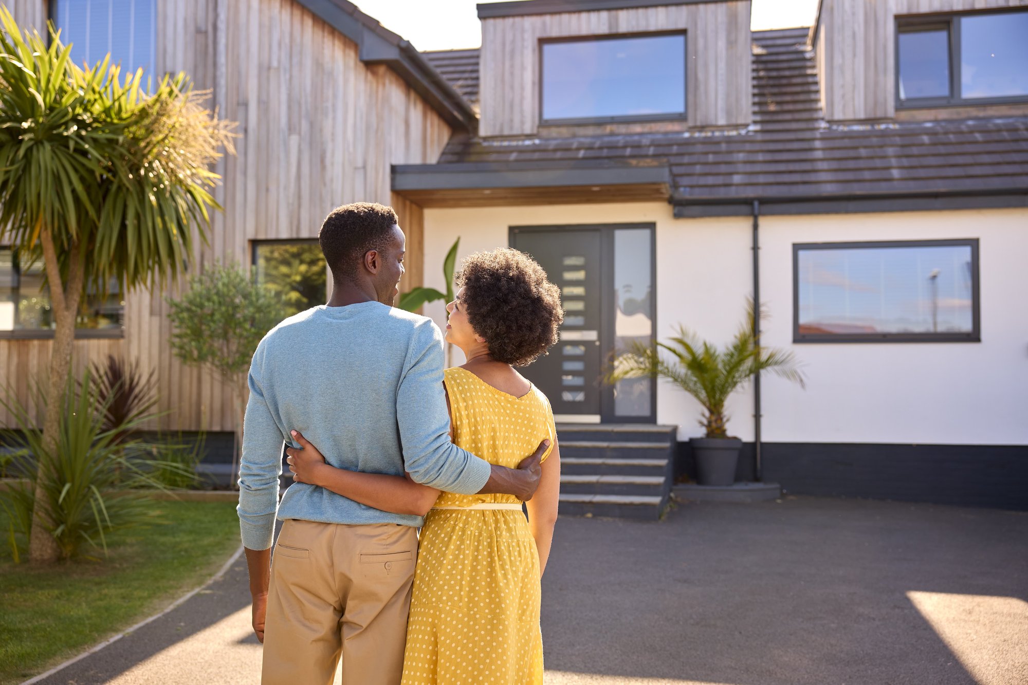 rear-view-of-couple-standing-in-driveway-in-front-2023-11-27-05-05-31-utc